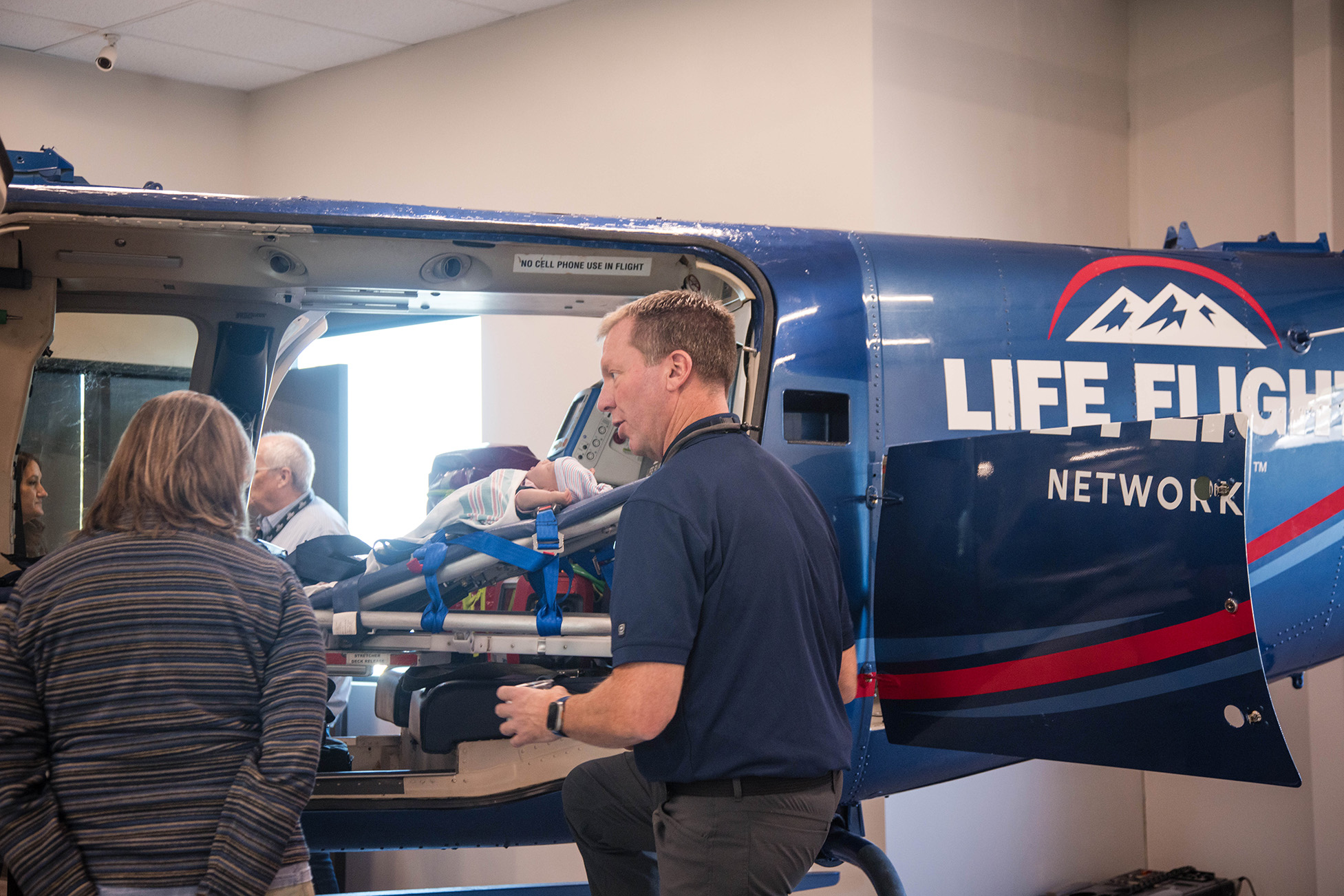 Life Flight Network staff load a patient stretcher into a helicopter during a medical transport demonstration.