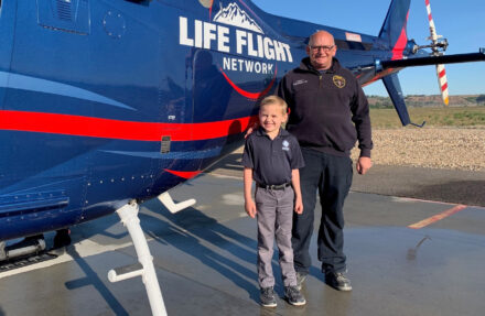 Young boy and older man pose in front of a Life Flight Network helicopter