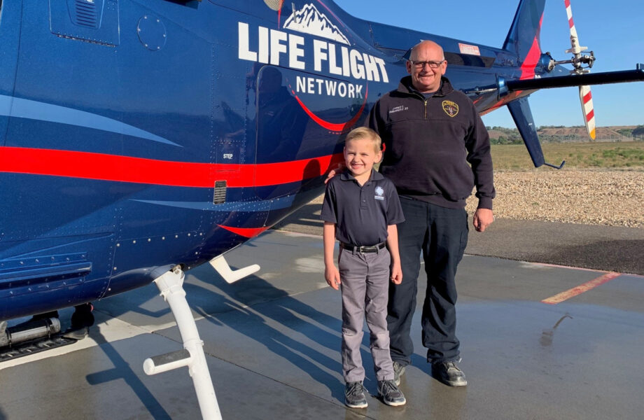 Young boy and older man pose in front of a Life Flight Network helicopter
