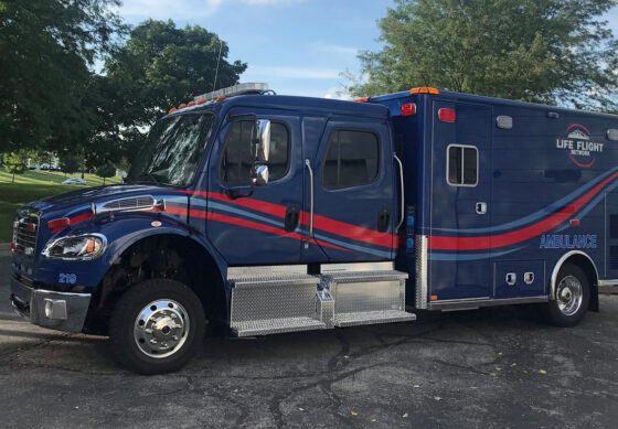 Life Flight ground ambulance parked with trees in background