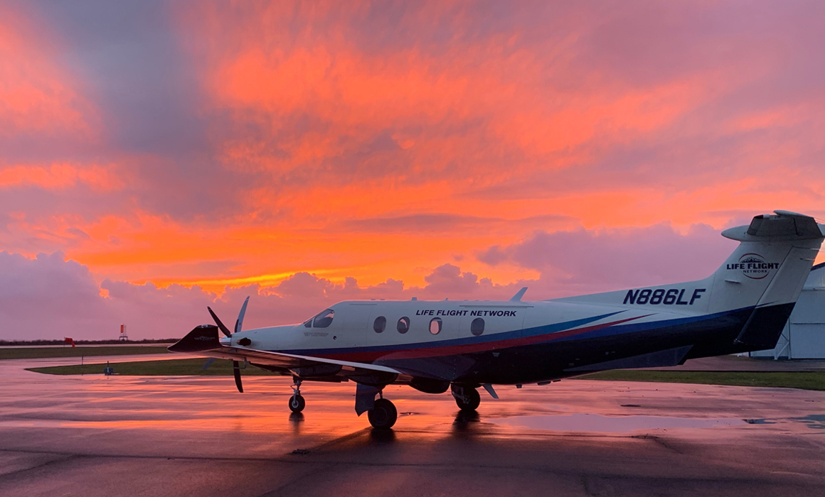 The PILATUS PC-12 NG airplane is seen with a dramatic orange and purple sunset in the background