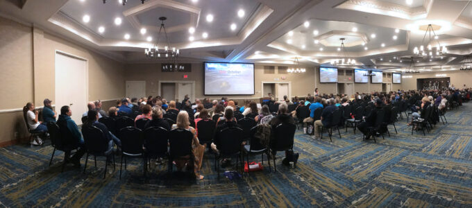 Large conference hall filled with people watching a presentation on trauma and critical care