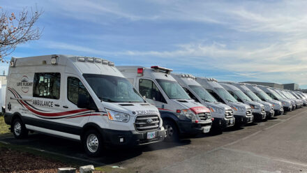 A row of ground ambulances are lined up and fade into the distance