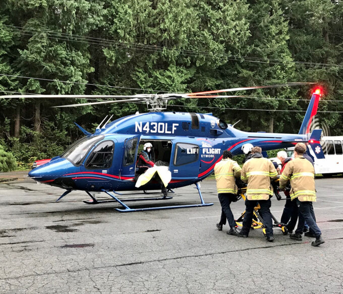 A flight nurse and three EMS technicians wheel patient to waiting helicopter with crew waiting to receive