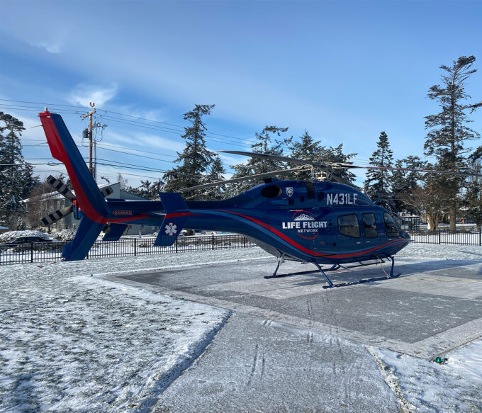 Helicopter sits atop a snow-covered landing pad awaiting take off