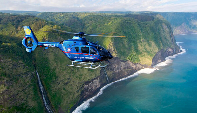 A Life Flight Network medical helicopter flies along the dramatic cliffs and waterfalls of Hawaii’s coastline, providing rapid emergency air transport across the islands.