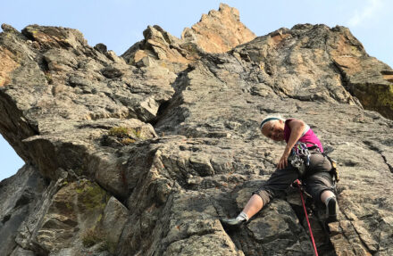 Older woman repels down a rock face