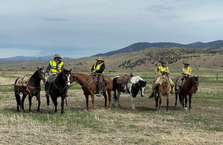 A group of people are seated on horseback in a high-desert landscape